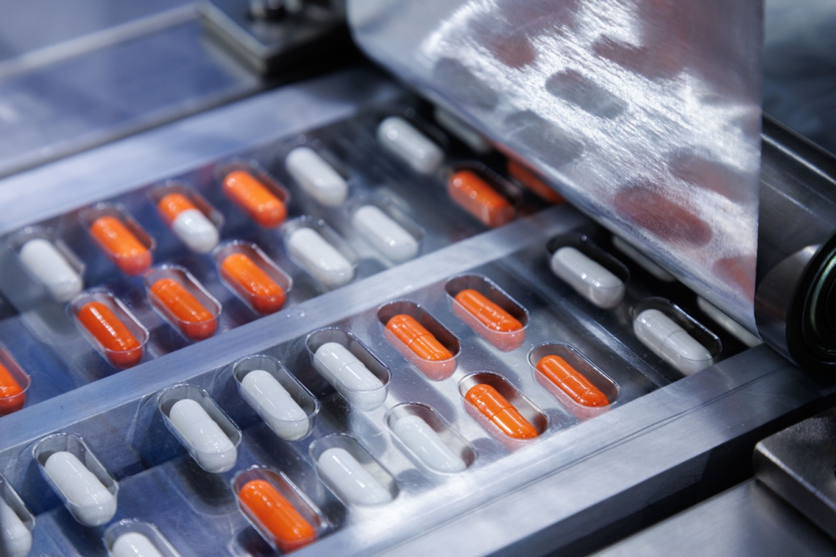 Orange and white pills being packaged in plastic packaging